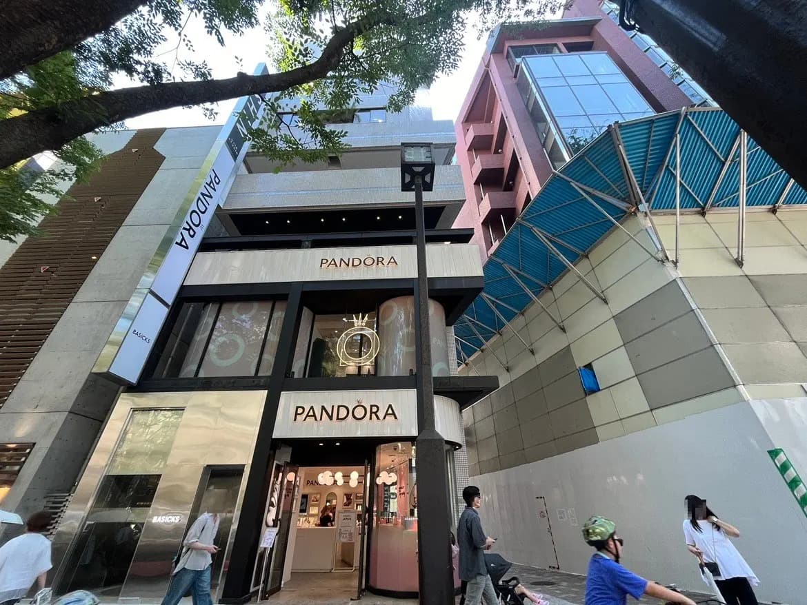 - パンドラの店舗外観、モダンなデザインと大きな窓、通行人が行き交う賑やかな通りの様子