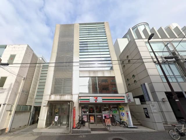 - 都市型のビルの外観、1階にセブンイレブンの店舗があり、周囲の建物とのコントラストが印象的な景観