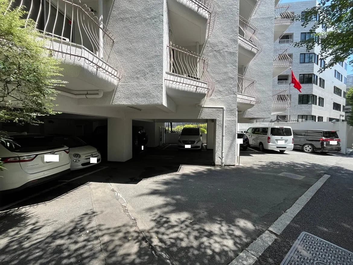 - 住宅の駐車場、白い建物の隣に並ぶ複数の車、日差しが差し込む快適な環境