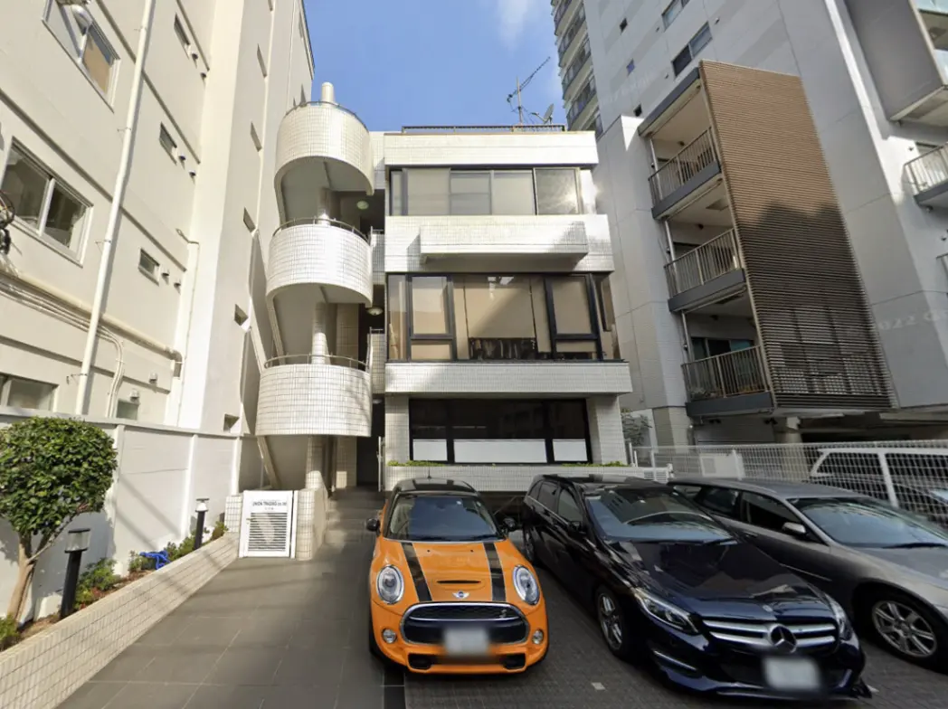 - 現代的なデザインの建物外観、螺旋階段とカラフルな車が並ぶ駐車場のシーン