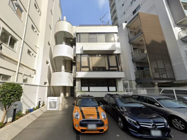 - 現代的なデザインの建物外観、螺旋階段とカラフルな車が並ぶ駐車場のシーン
