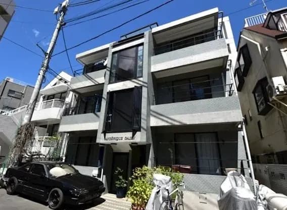 - モダンな外観のアパートメントビル、グレーのタイル張り、広いバルコニーと大きな窓、周囲の日差しがふりそそぐ景観