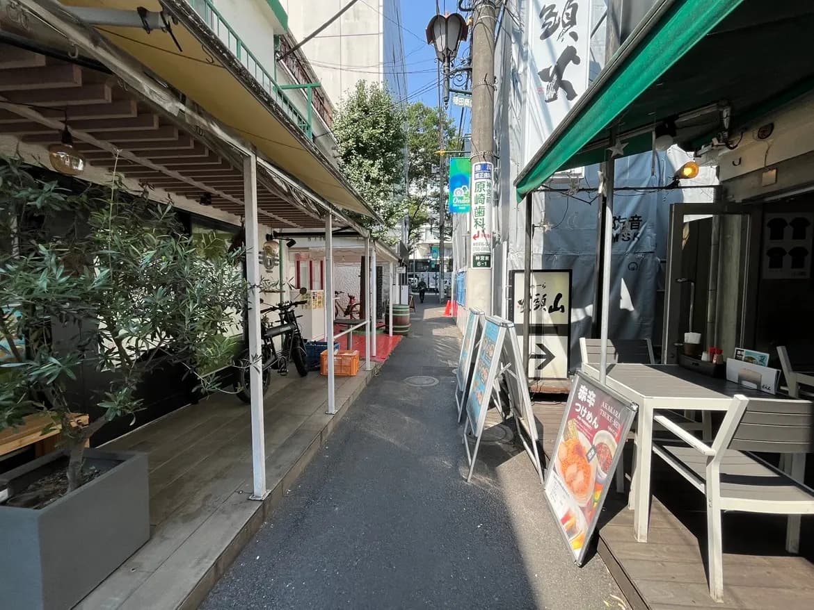 - 魚料理専門店の外観、テラス席と看板メニューが並ぶ狭い通りの風景