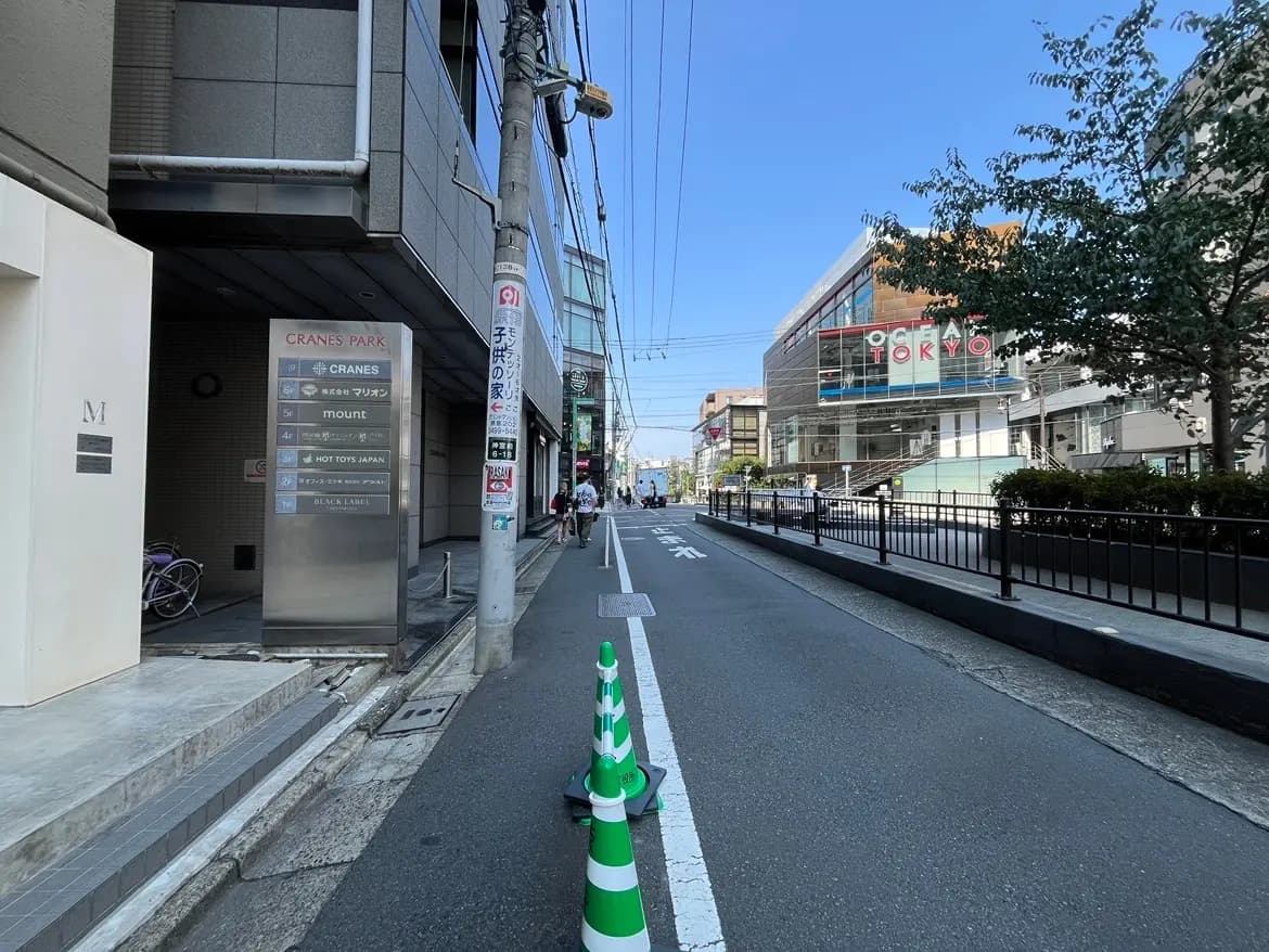 - クレインズパークの案内看板と周辺の商業施設、青空が広がる都市の風景、道路脇に並ぶ自転車と交通標識