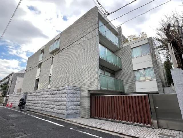 - モダンな外観の住宅、ガラスバルコニーとコンクリート壁を持ち、角度から撮影された街並みの一部