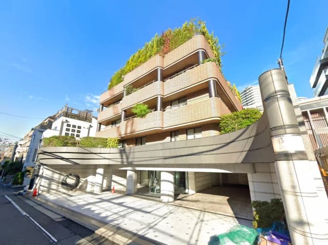 - 緑豊かな屋上庭園が特徴のモダンなマンション外観、洗練されたデザインと明るい空の背景