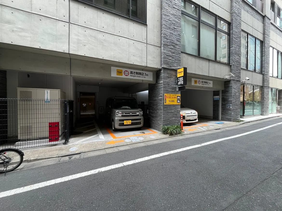 - 駐車場の入り口があるビル、満車の表示と高さ制限の看板、左側には自転車が駐輪されている様子