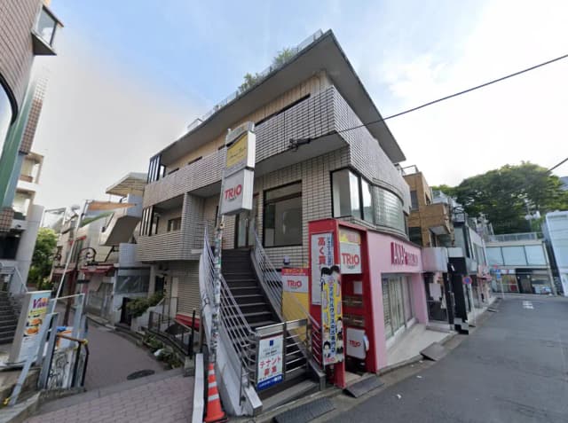 - 都市型の三階建てビル、外観はタイル張りで、階段と広い窓が特徴的な商業施設のエントランス