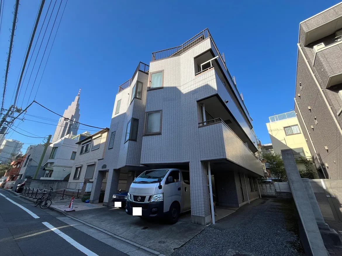 - 高層ビルの背景にあるモダンなアパートメント、駐車スペースと自転車の停まる道路風景