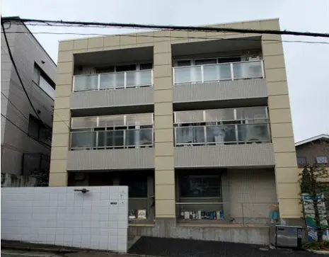 - 近代的なデザインのマンション外観、3階建てでバルコニーが特徴的、周辺に住宅が広がる地域の風景