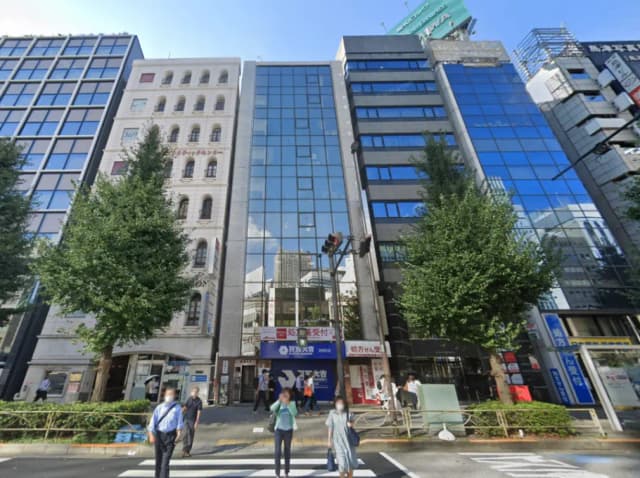 - さまざまなデザインのビルが並ぶ都市の風景、通行人が交差点を横断する様子が見える街並み
