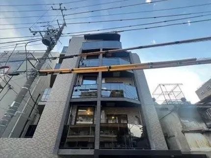 - モダンな外観のビル、ガラス張りのバルコニー、周囲の電柱や電線が見える都市の風景