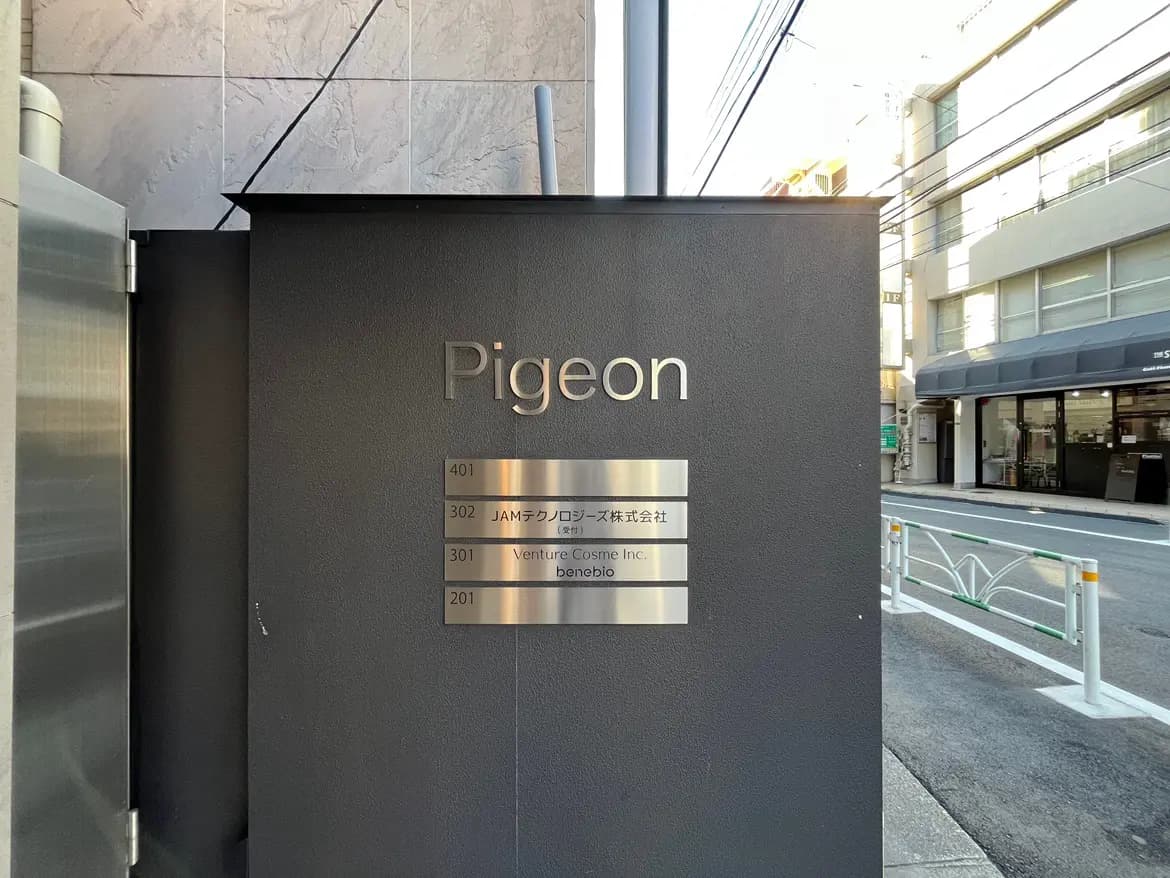 - 「Pigeon」と書かれた看板が設置された建物の入口、会社名や部屋番号が掲示されたスタイリッシュなサインボード