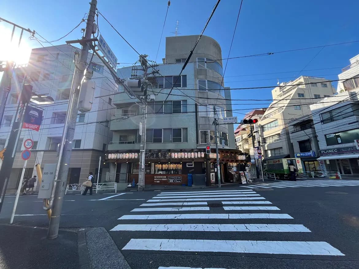 交差点の風景、ビルと飲食店があり、青空と電柱や交通信号が写っている都市の風景