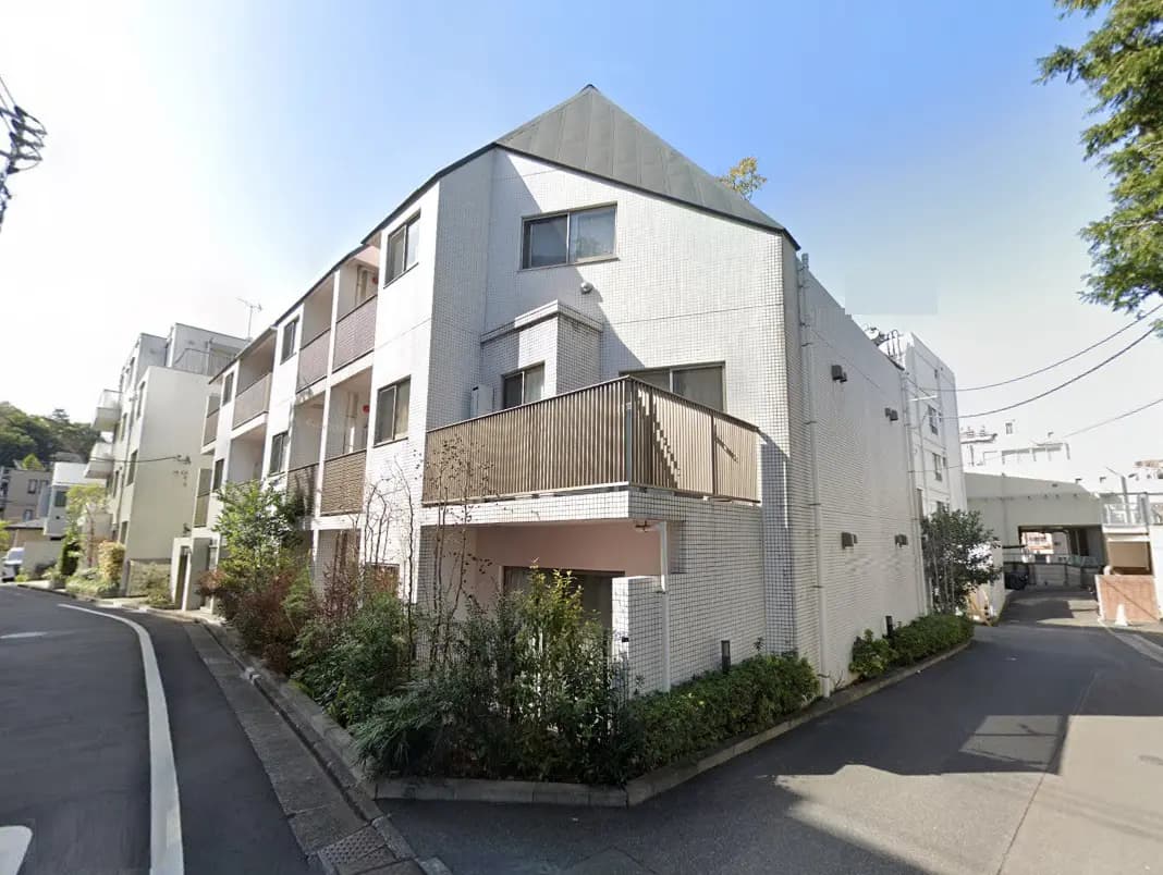 - 自然光が降り注ぐ白い外壁のアパートメント、バルコニーと洗練されたデザインの周辺風景が特徴的