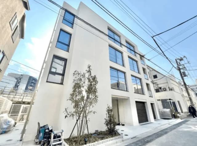 現代的な外観の都市型マンション、白い壁と大きな窓、青空と周囲の建物が見える景色