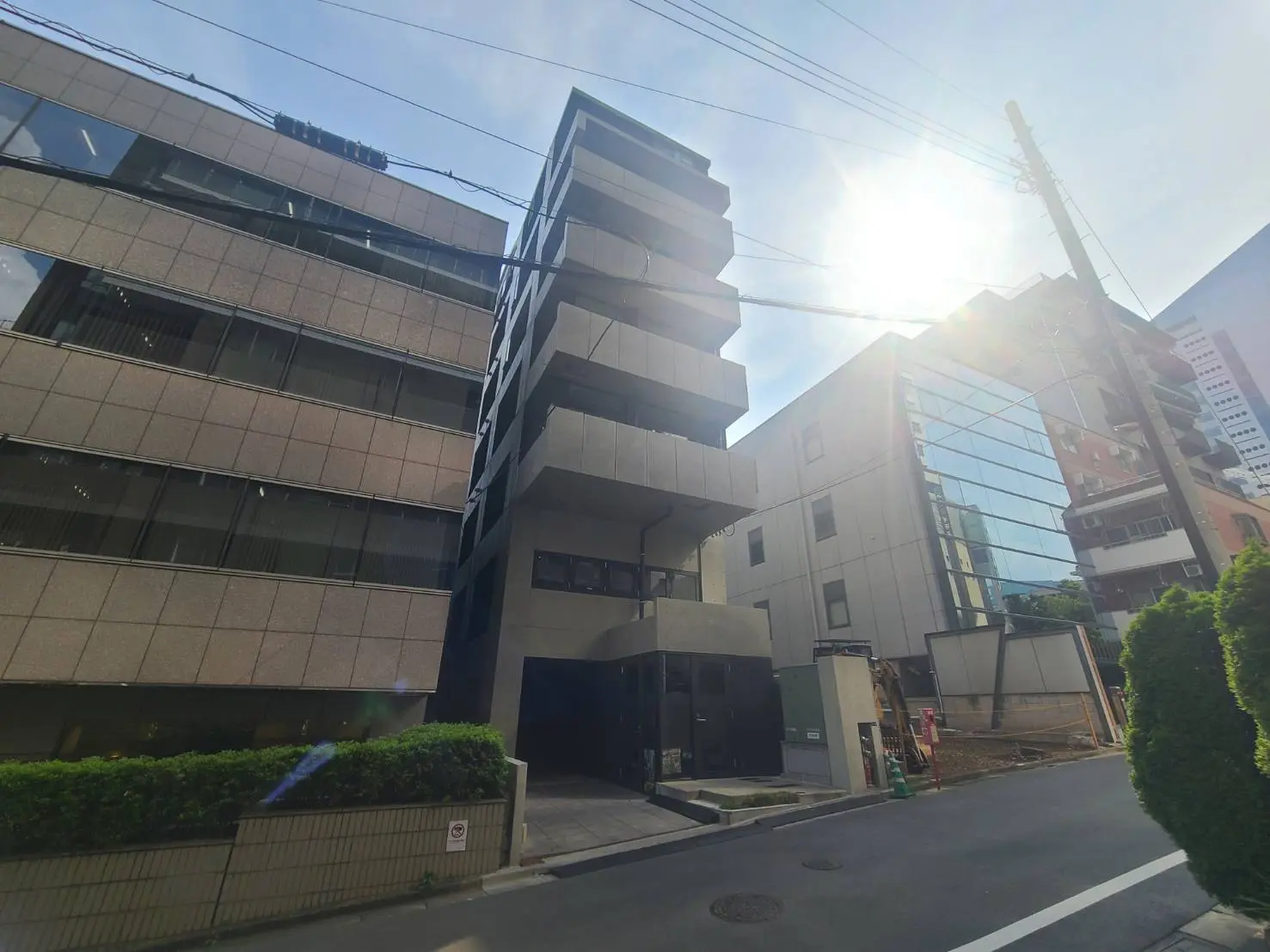 - 光が差し込む都市型のビルの外観、隣接する建物とのコントラストを持つ現代的なデザイン