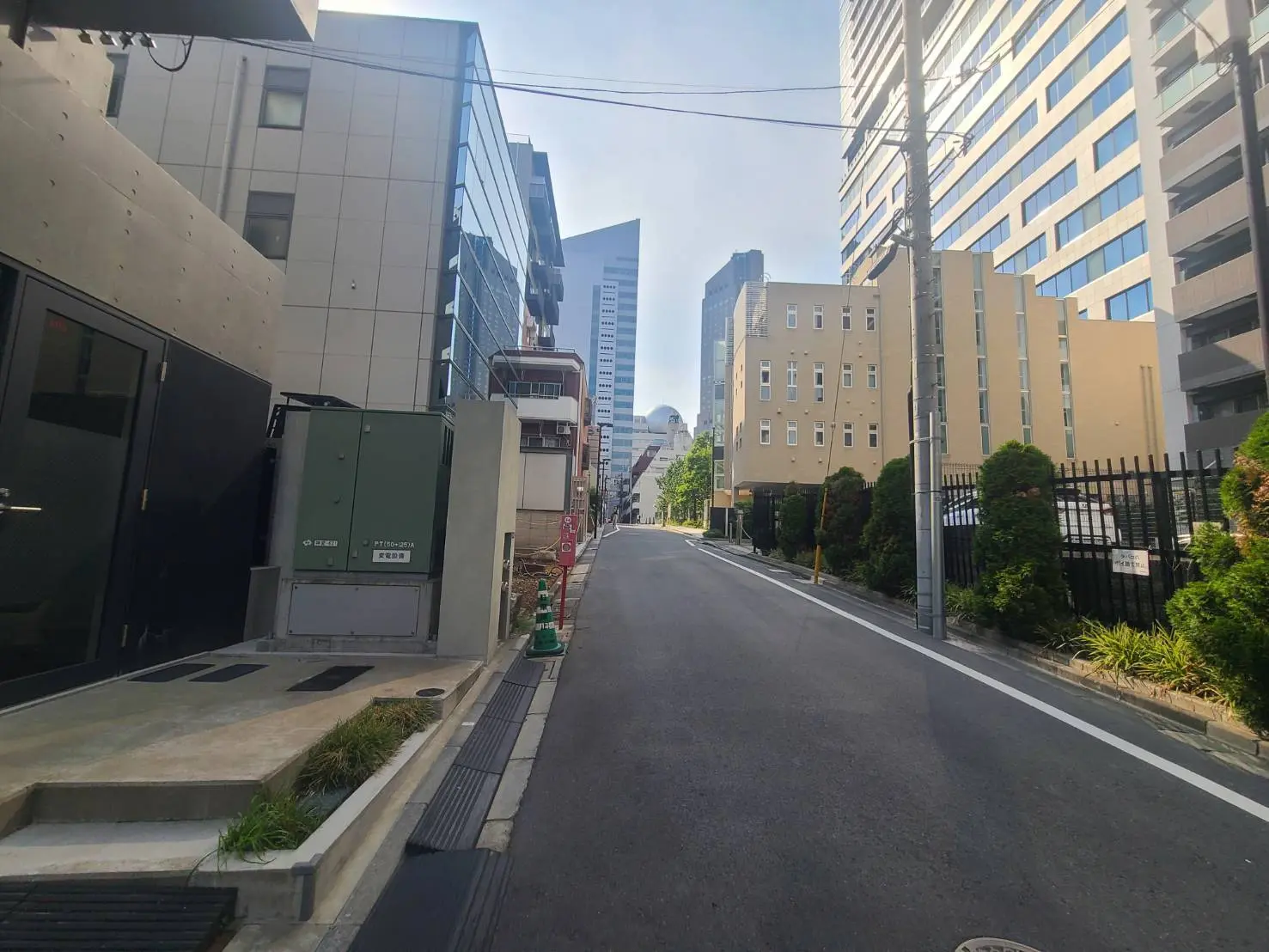 - 都市の風景、コンクリートの建物とガラス張りのビルが並ぶ通り、静かな住宅街の様子