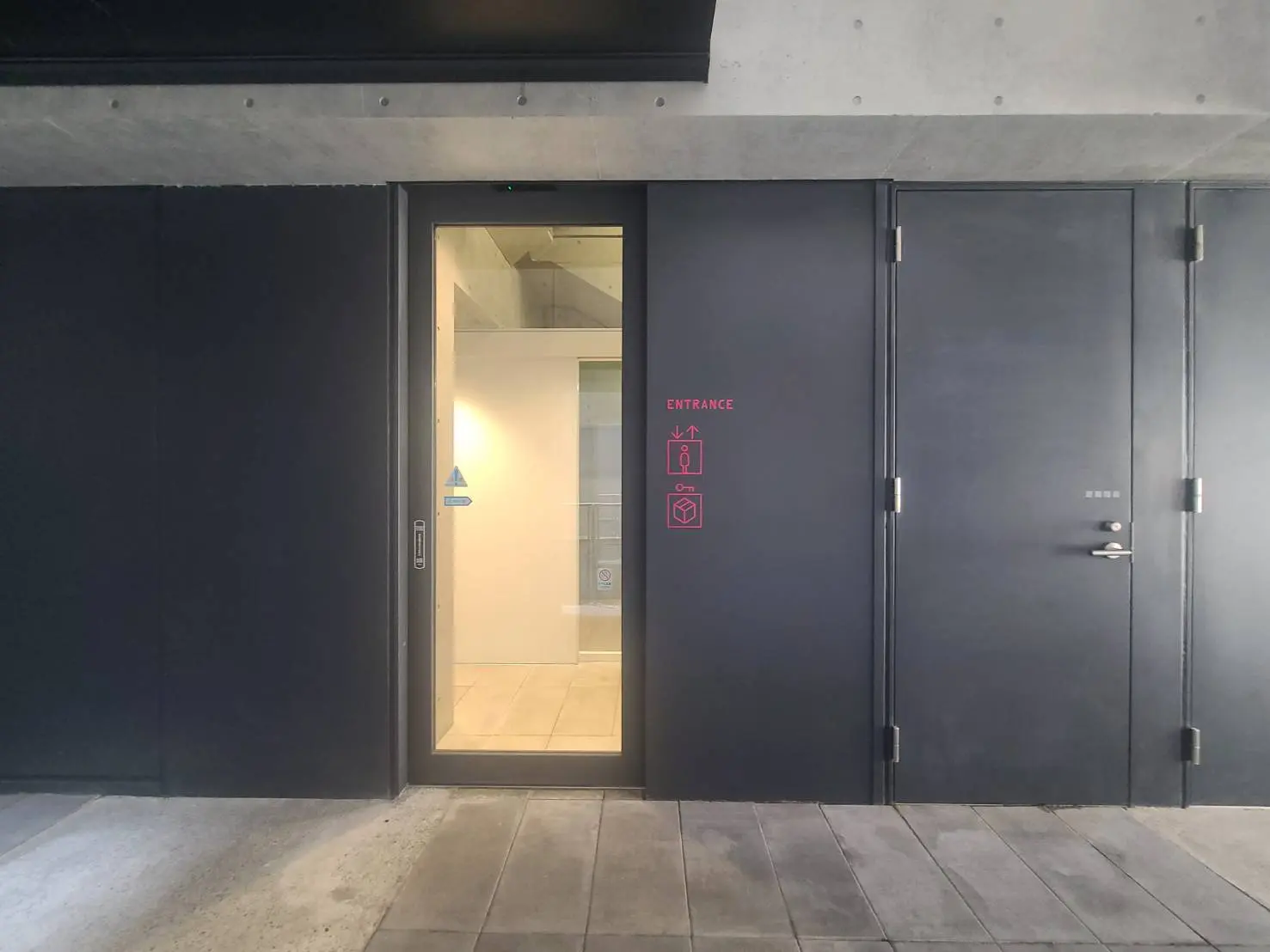 - モダンなデザインの建物の入り口、黒いドアと透明なガラス、大きな窓から光が入る明るいエントランス