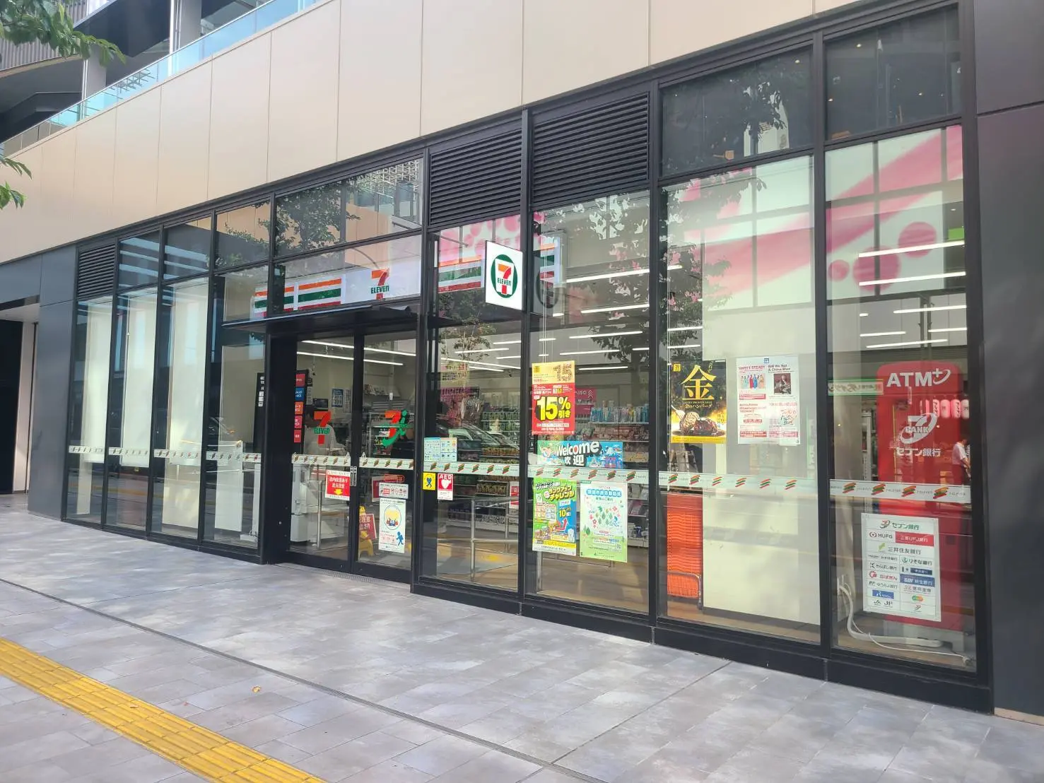 - 現代的なデザインのセブンイレブンの店舗外観、大きなガラス窓で明るい雰囲気、店内の商品が見える様子