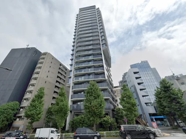 - 限定的な都市景観を背景にした現代的な高層マンション、周囲には緑豊かな木々と他のビルが立ち並ぶ風景
