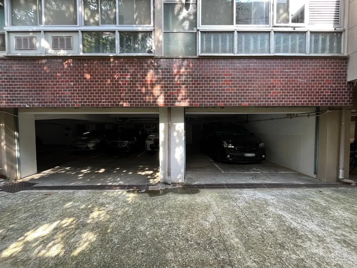 - 駐車場の下にある建物の外観、レンガの壁と複数の自動車が停車している様子