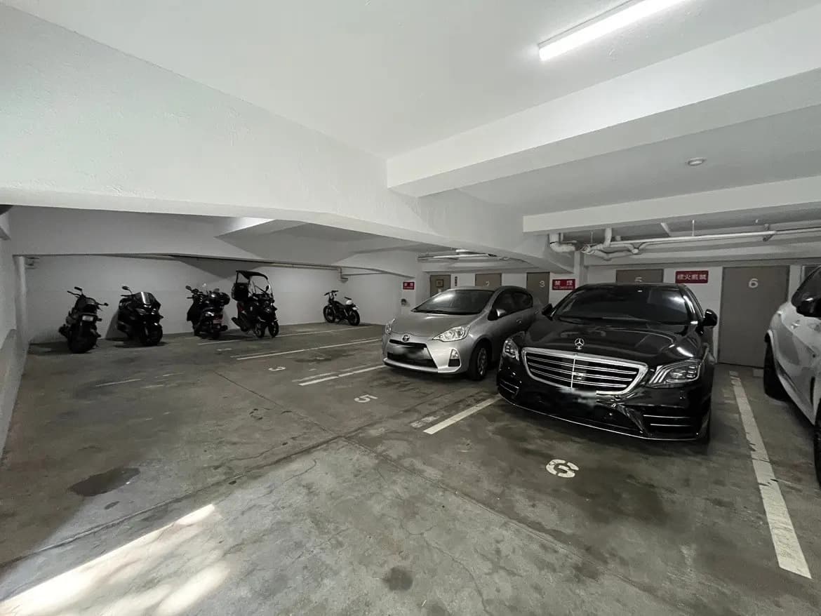 - 車とバイクが駐車された明るい屋内駐車場、白い壁とスリムなデザインのインテリア