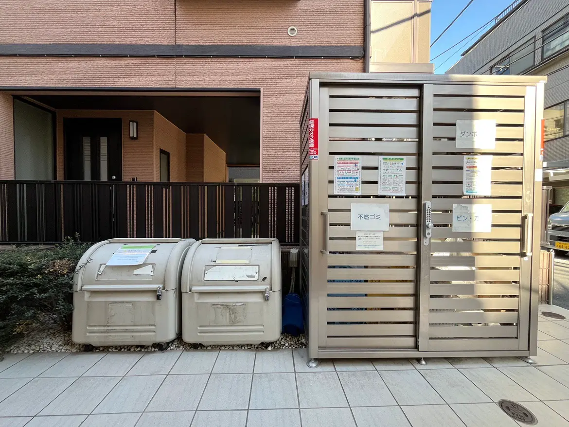 - 集合住宅の玄関前に設置されたゴミ捨て場、分別用のゴミ箱と周囲の清掃されたエリア