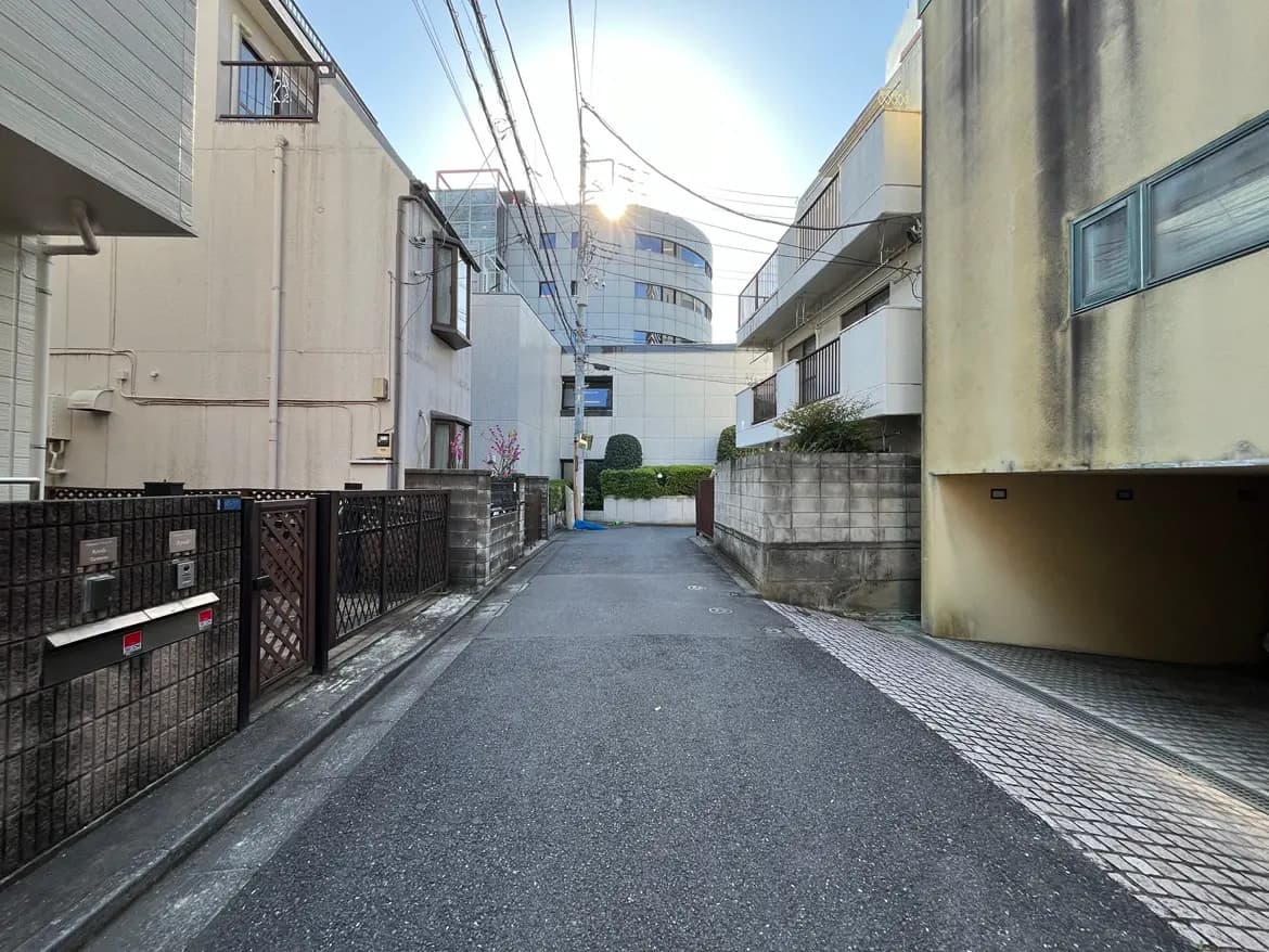 - 都市の住宅街の狭い路地、古い建物と近代的な建物が並ぶ風景、電線が交差する様子