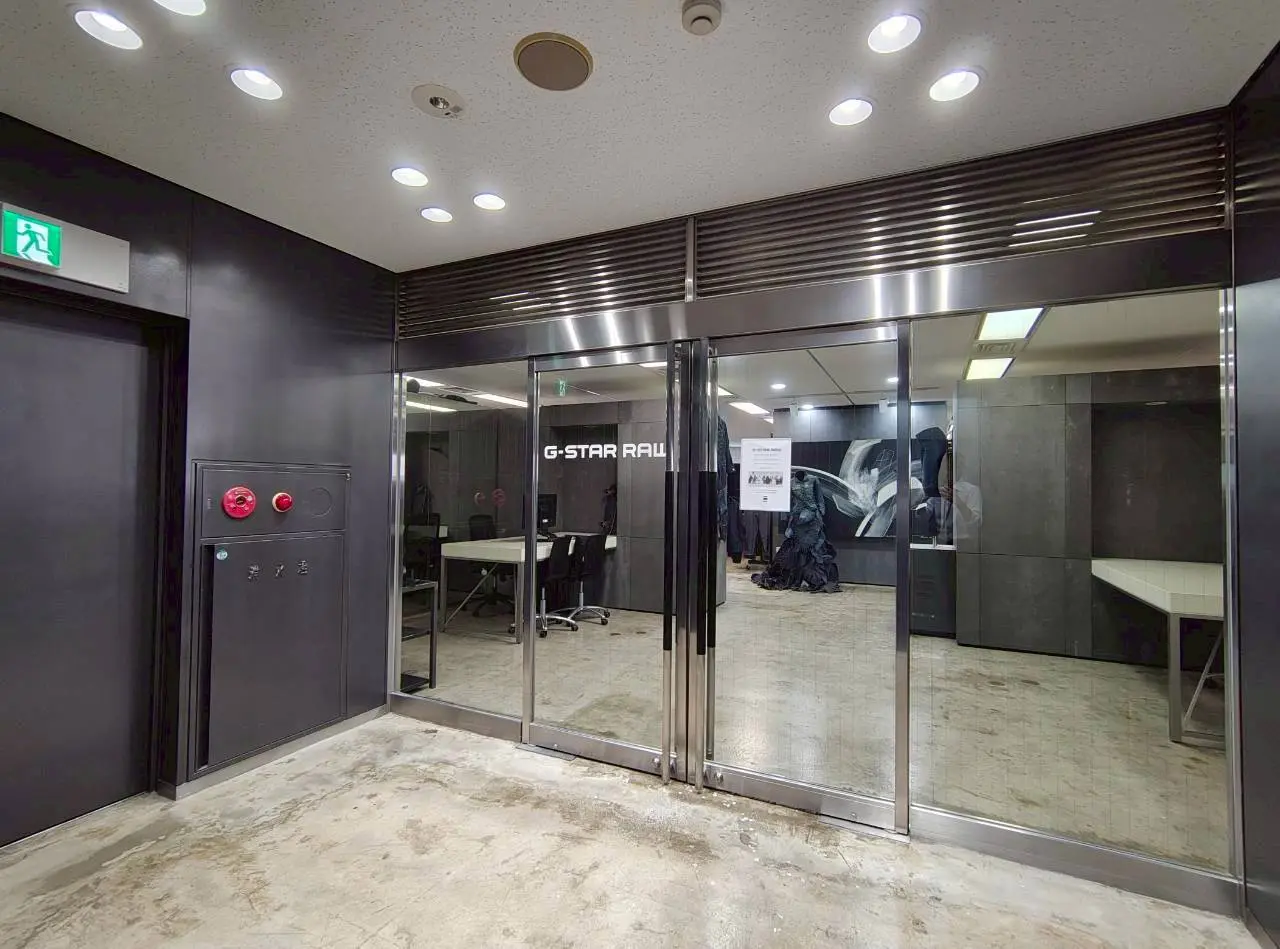 - G-Star RAWの店舗エントランス、モダンなデザインのガラス扉とシンプルな内装、照明が明るい空間