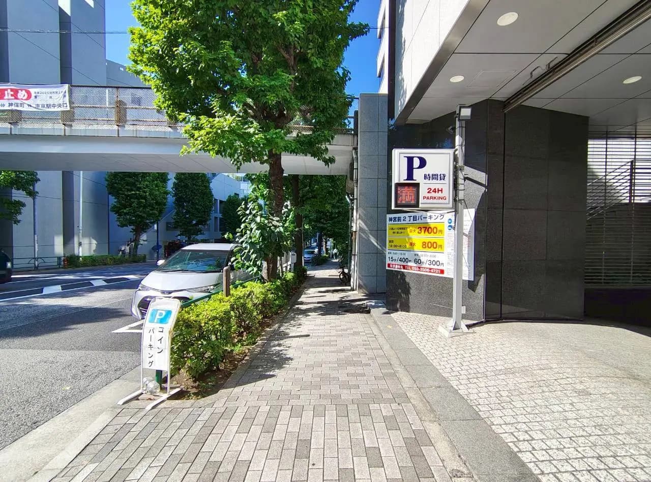 - 駐車場の看板と緑豊かな街路樹が並ぶ歩道、晴天の下で明るい風景