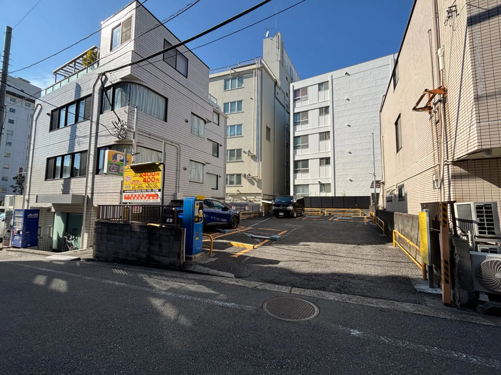 - 駐車場のあるビル群、青空の下に広がる都市の風景と交通標識のある街角の様子