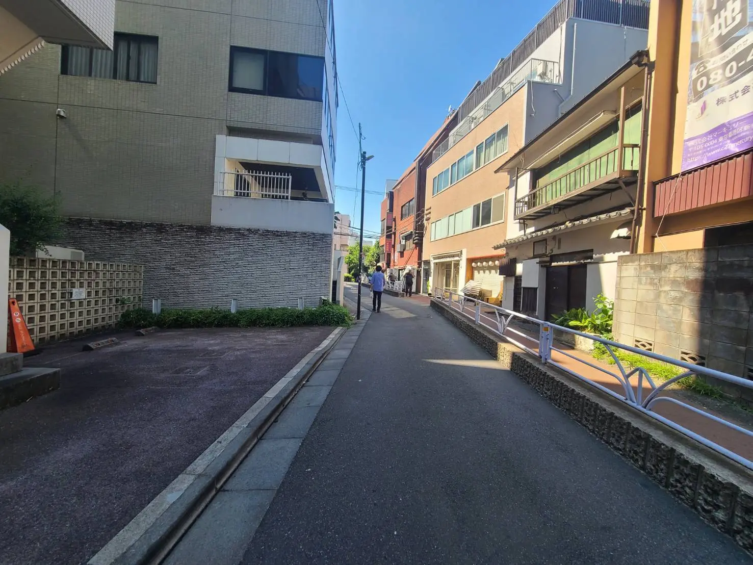 - 魅力的な都市の通り、住宅や店舗が並ぶ風景、青空の下で歩く人々が見える景色