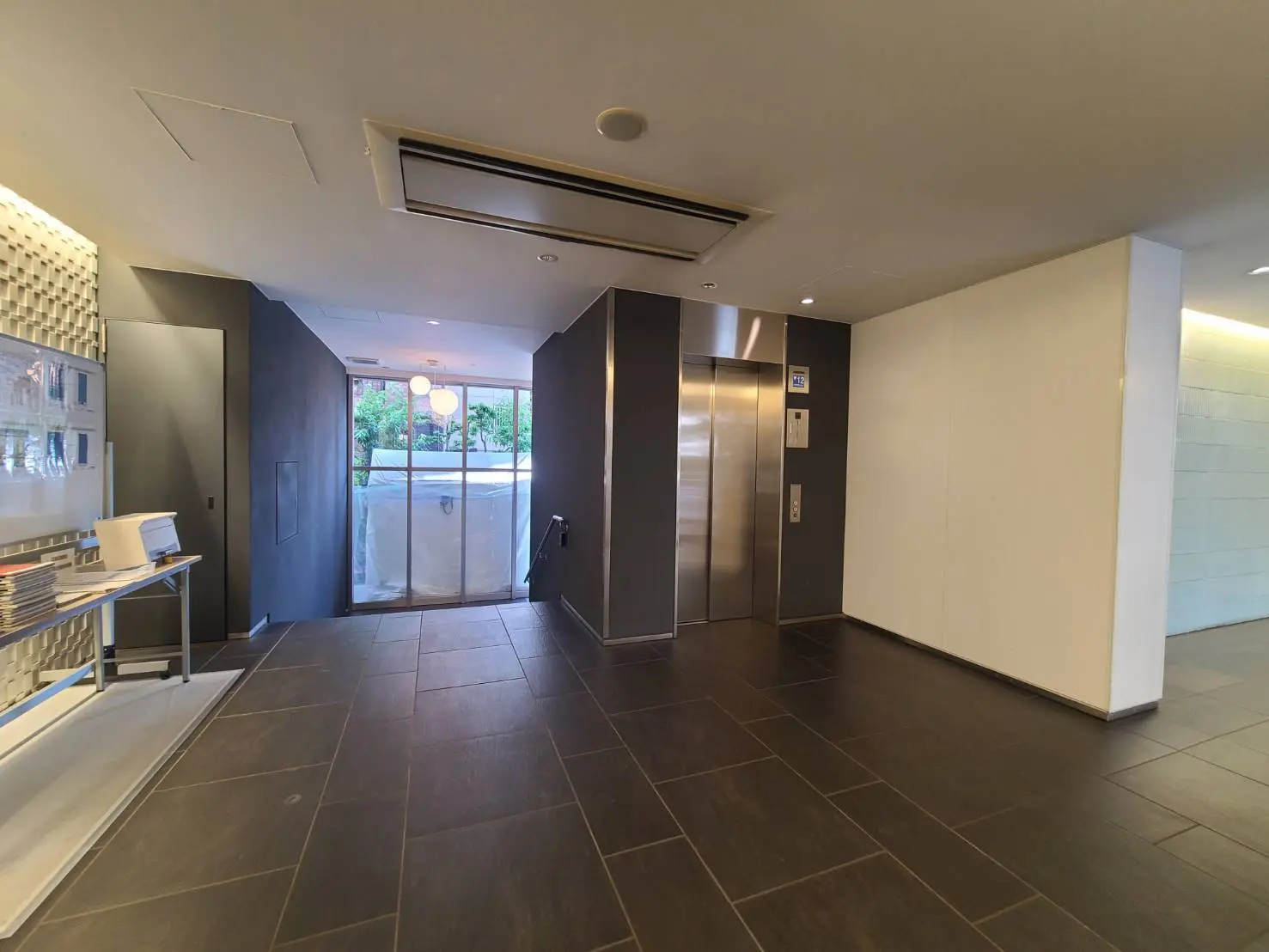 - モダンなエントランスホール、壁に沿ったスタイリッシュなデザイン、明るい照明とエレベーターのある広々とした空間