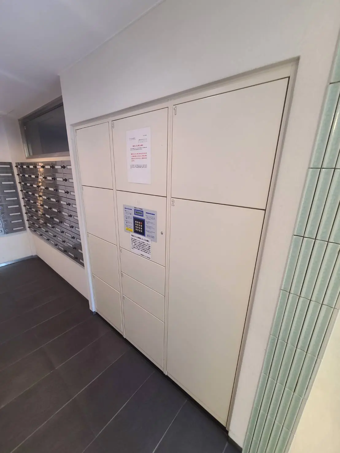 - シンプルなデザインの宅配ボックスと郵便受け、明るい照明があるエントランスホールの内部の様子