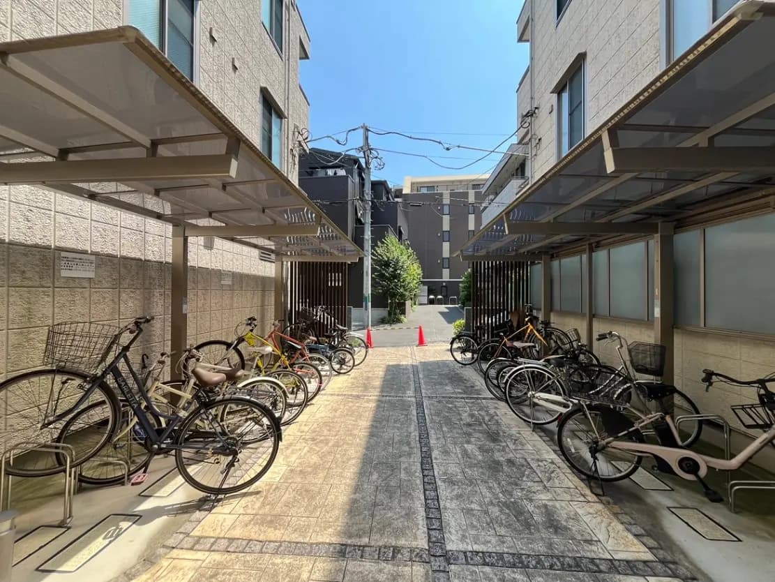 - 複数の自転車が整然と並ぶ屋根付きの駐輪場と、明るい青空が広がる風景
