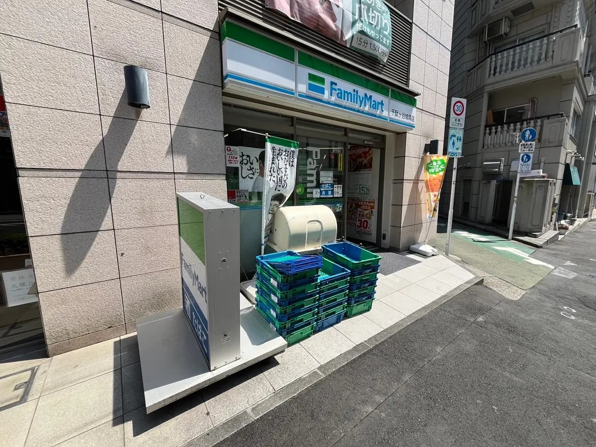 - ファミリーマートの店舗前、青いカゴと看板、日差しを浴びた外観の様子