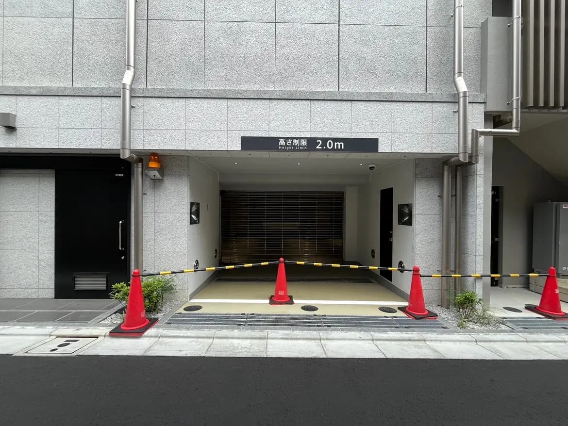 - 駐車場入り口の様子、制限高さ2.0mの表示、赤いコーンとバリケードが設置された現場の風景