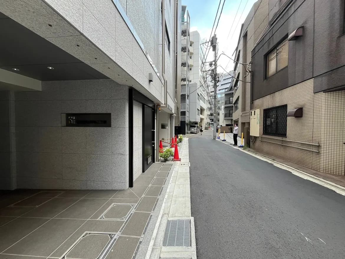 - 都市の住宅街を映した風景、近代的な建物と狭い通り、エントランスが見えるアプローチ