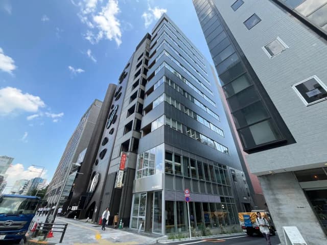 - モダンなビルが立ち並ぶ都市の風景、青空と白い雲が広がり、街の賑わいを感じさせる光景
