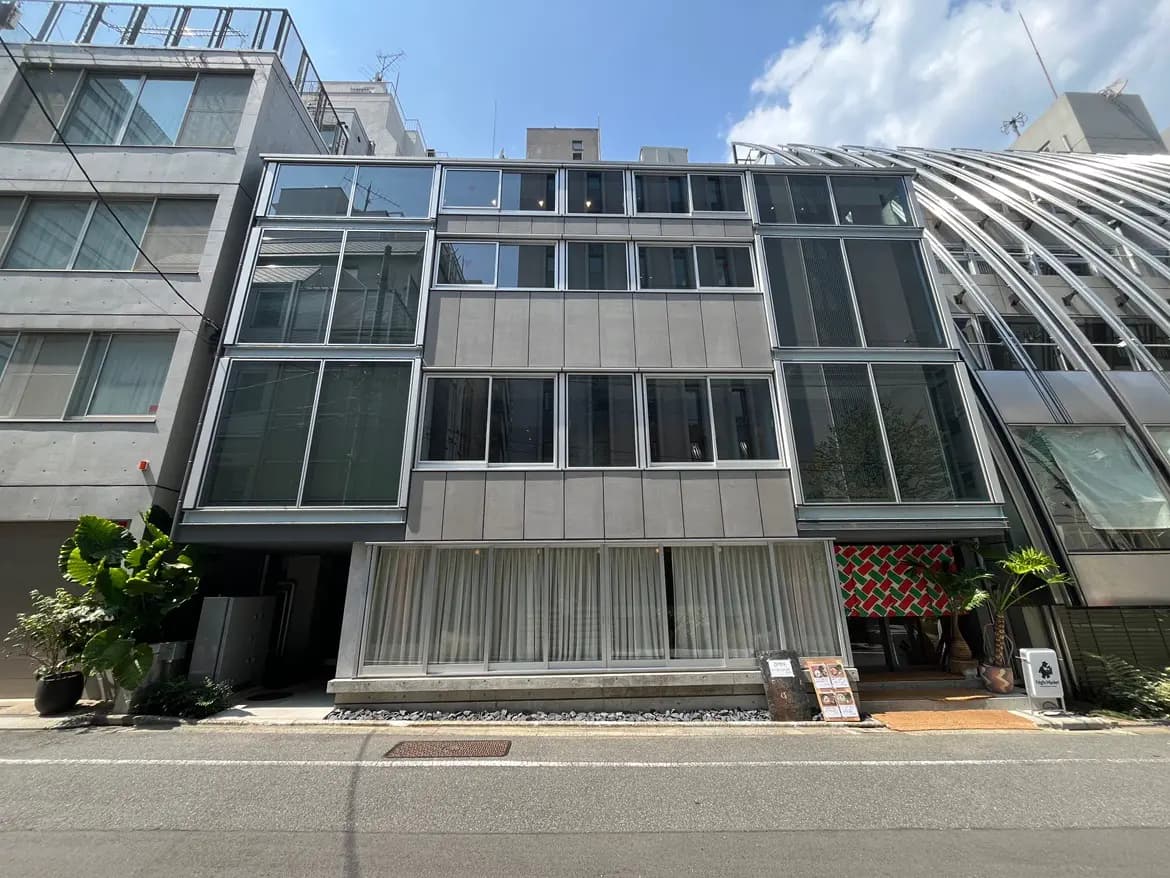 - 現代的なデザインのビル外観、テラスと大きな窓が特徴、街の景観に溶け込むスタイリッシュな建物