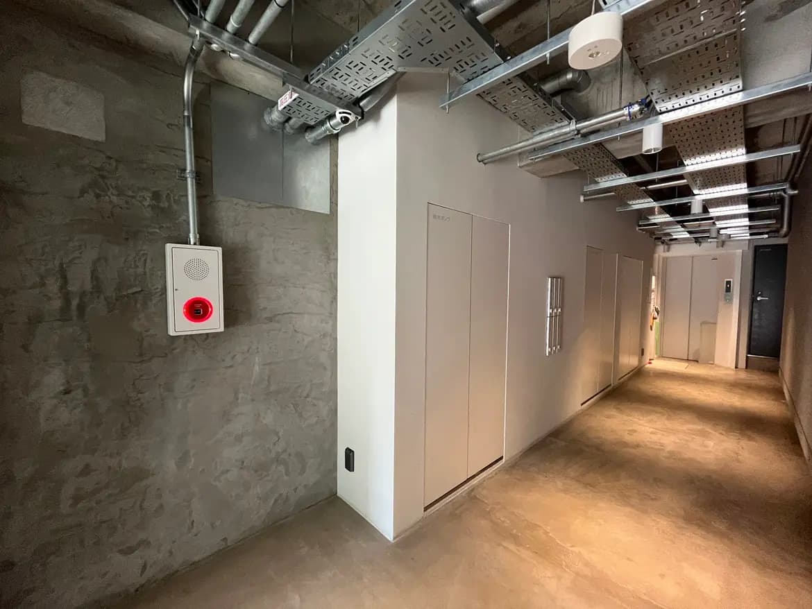 - コンクリート壁の室内、赤い警告灯とスピーカーが取り付けられた設備のある空間
