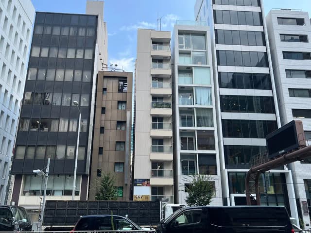 - 都市のビル群、異なるデザインの高層ビルが立ち並び、明るい空の下での風景