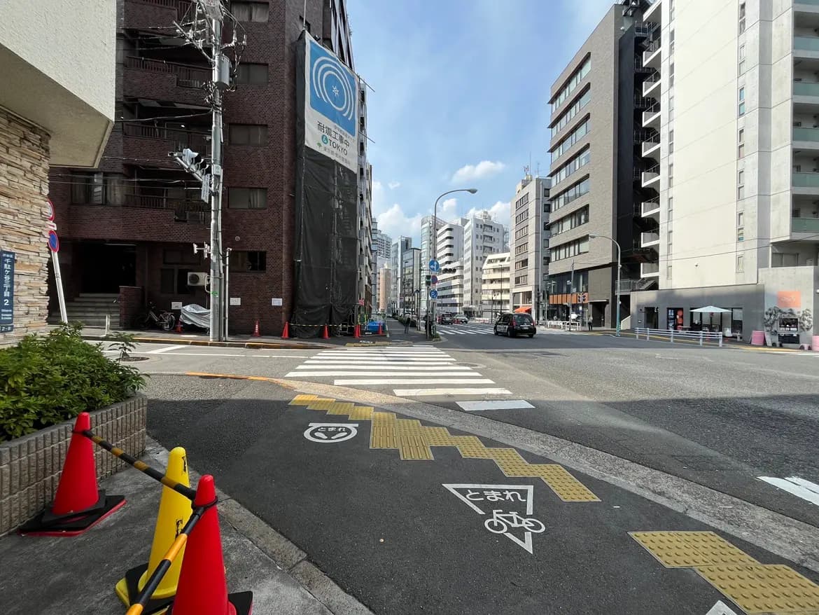 - 都市の交差点、周囲には高層ビルやマンションが立ち並び、自転車専用の道路標識と信号機が見える風景