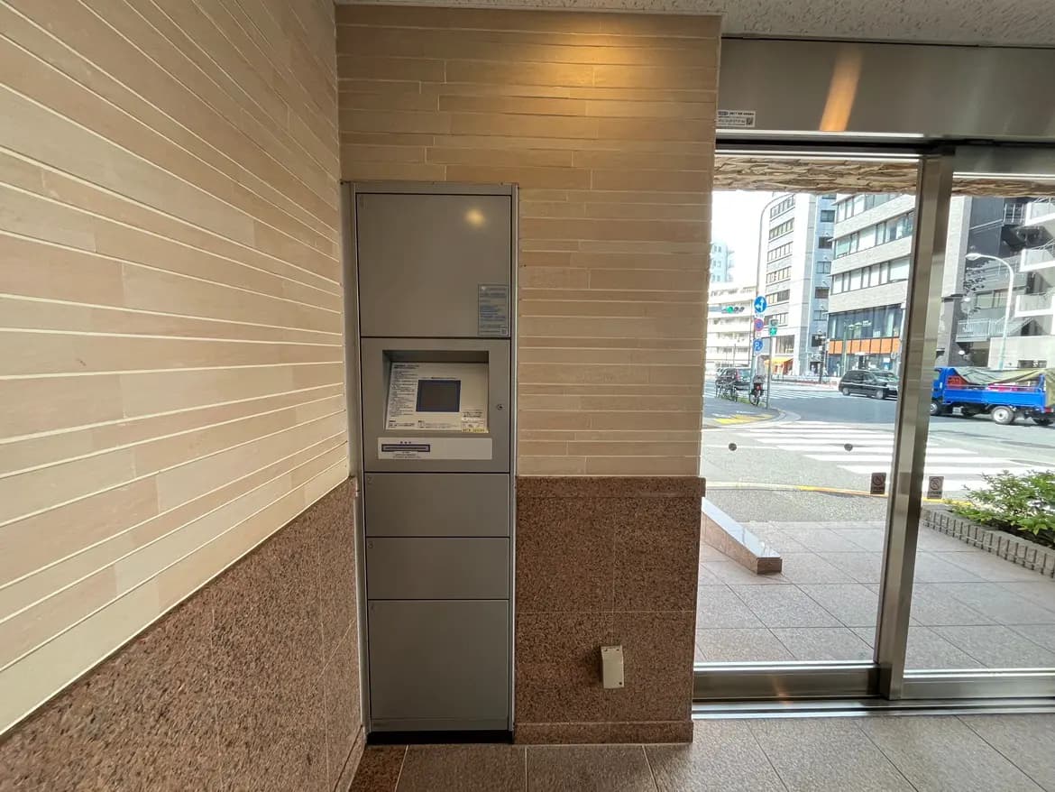 - 銀色のATMが設置された店舗の内部、明るいタイル壁と開放的な入口が見える風景
