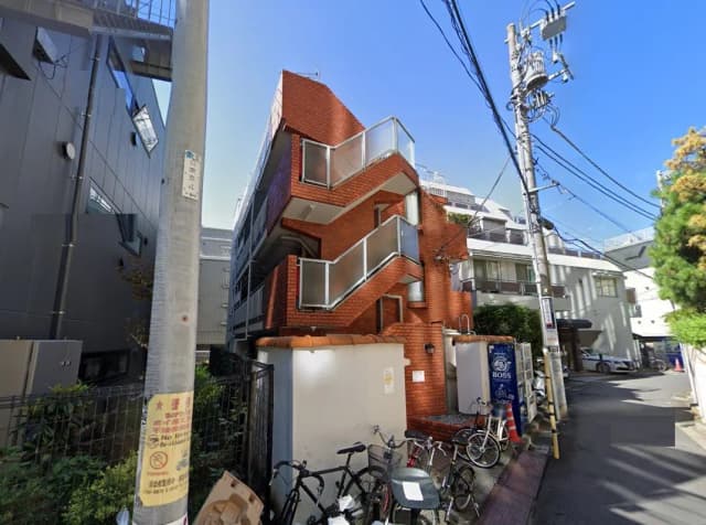 - レンガ造りのアパート外観、階段が特徴的で周囲に自転車が置かれた狭い道沿いの景観