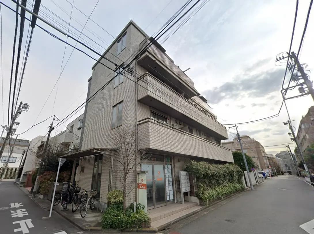 - モダンな外観のアパートメントビル、街路樹や自転車が配置された通りの風景、明るい空の下での景観
