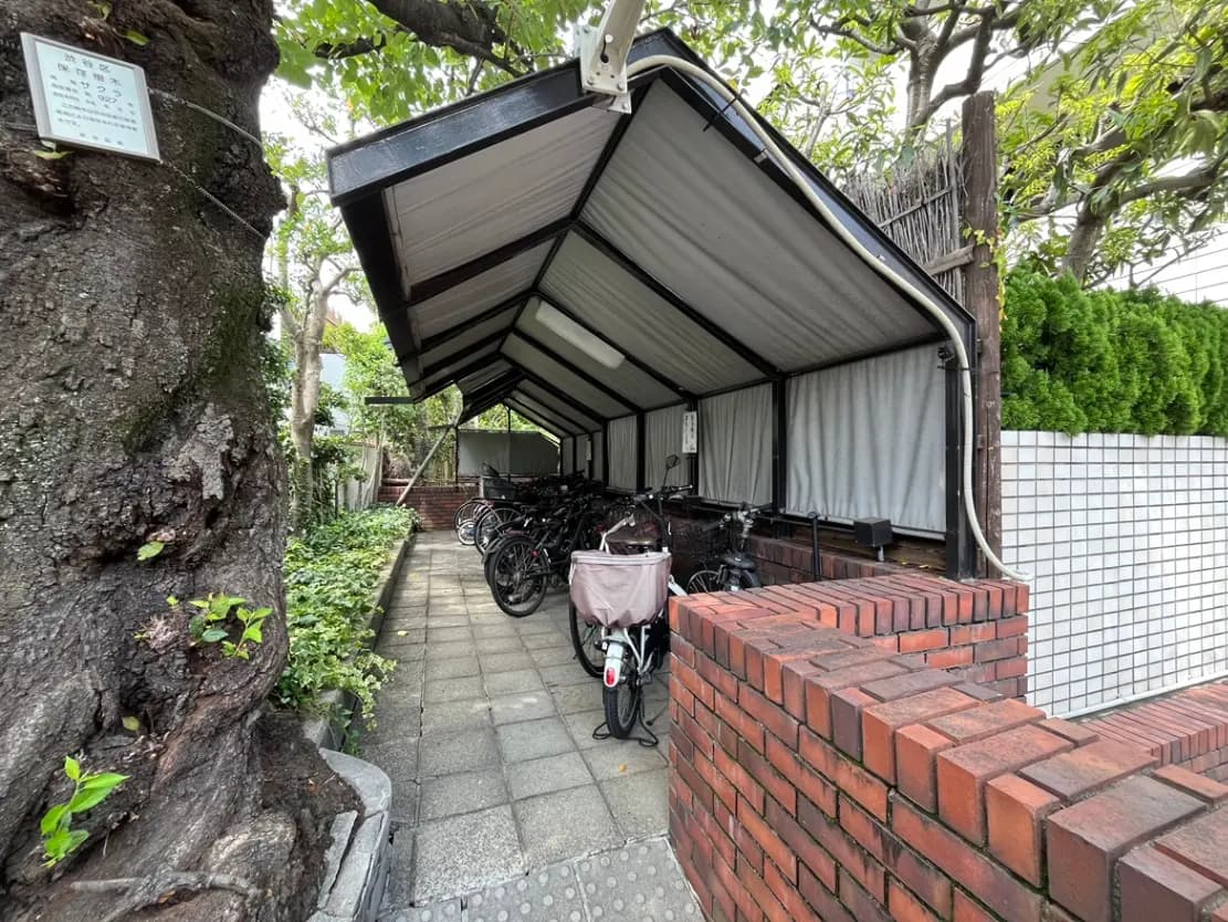 - 自転車が置かれた屋根付きの駐輪場と、周囲の緑豊かな環境を配した街の風景