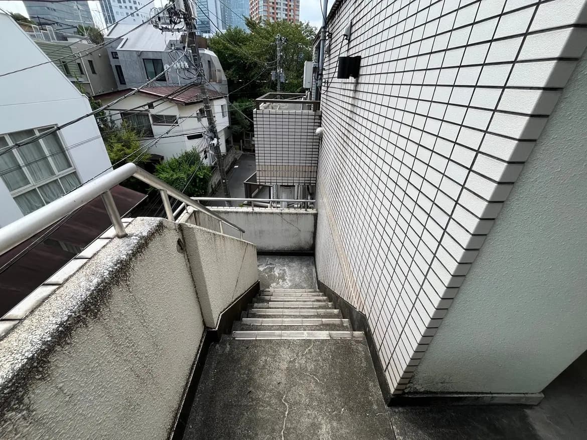 - 降りる階段とタイル張りの壁、周囲に見える住宅と電柱がある都市の風景
