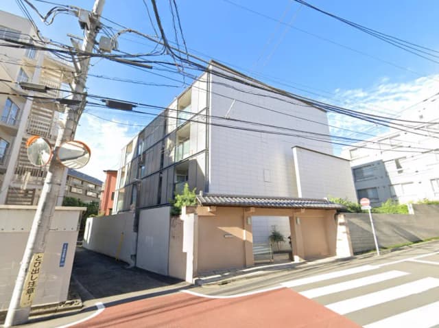 - 現代的な外観のアパートメントビルと伝統的な壁の入口、青空に映える建物と電線の風景
